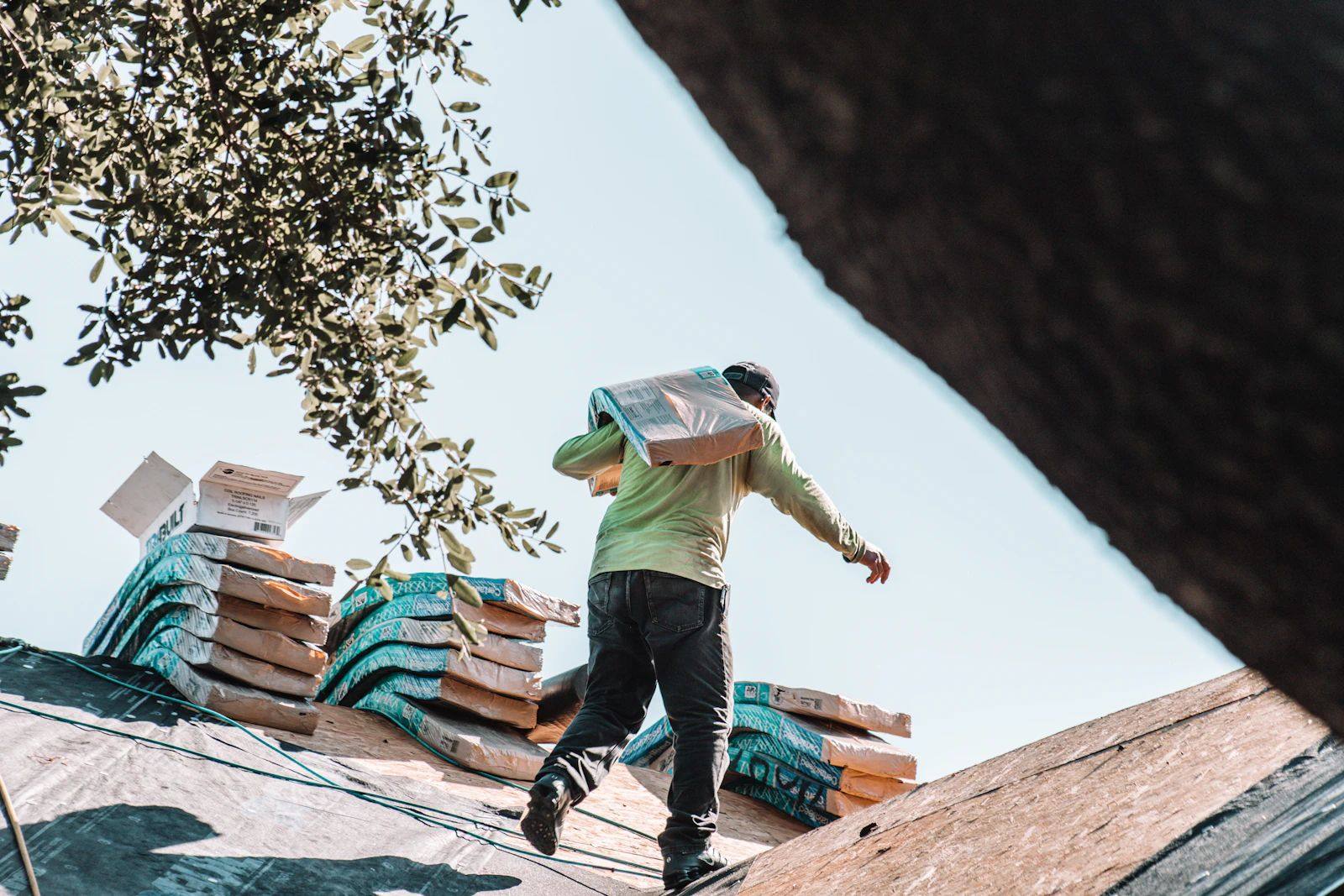 Roofer carrying shingles across a coastal roof