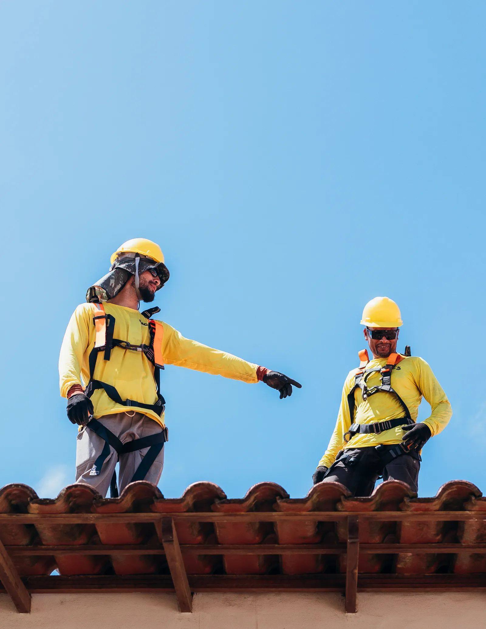 Roofers in safety gear on a tile roof